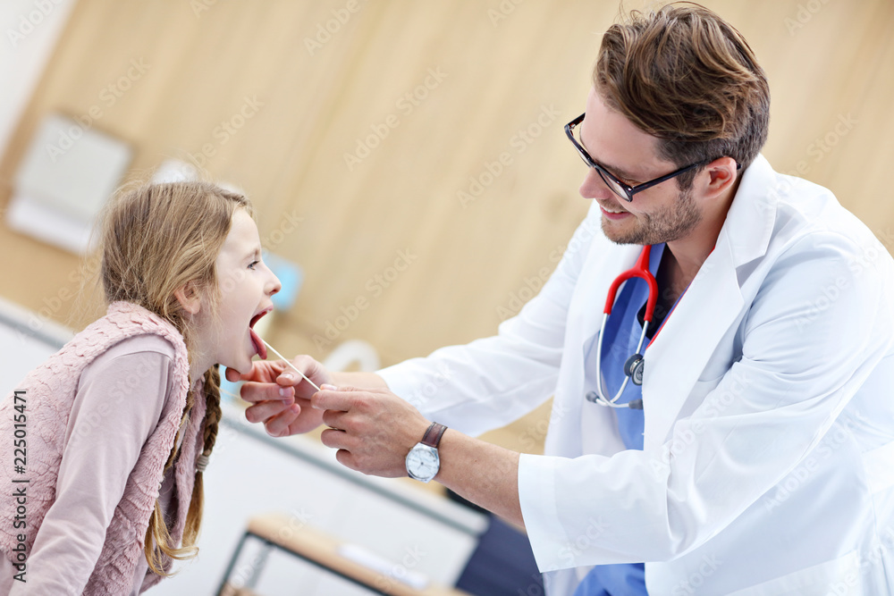 Fototapeta premium Little girl in clinic having a checkup with laryngologist