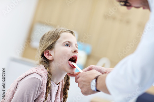 Little girl in clinic having a checkup with laryngologist