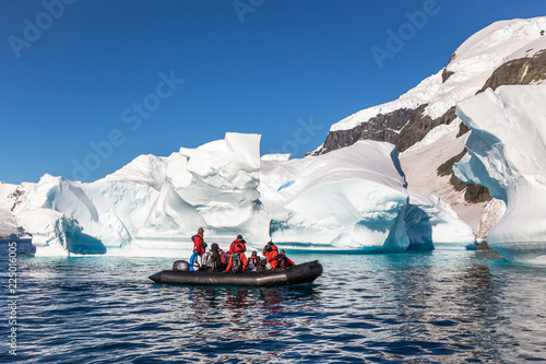 Boat full of tourists explore huge icebergs drifting in the bay