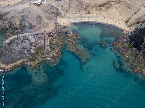 Vista aerea delle coste frastagliate e delle spiagge di Lanzarote, Spagna, Canarie. Bagnanti in spiaggia e nell’Oceano Atlantico. Papagayo