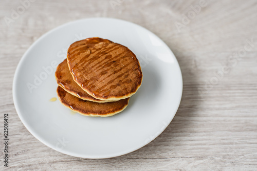 Still life morning breakfast of pancakes with honey on a white plate on a wooden background