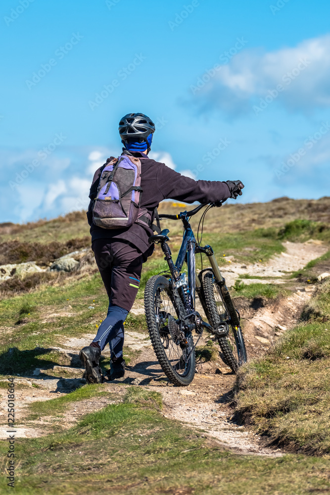 Sportsman is pushing his bike up on the mountain path Sportsman is pushing his bike up on the mountain path
