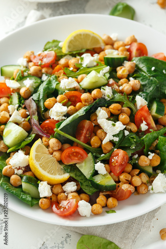 Chickpeas Salad with cucumber, tomatoes, feta cheese and green mix in a white plate. healthy food.