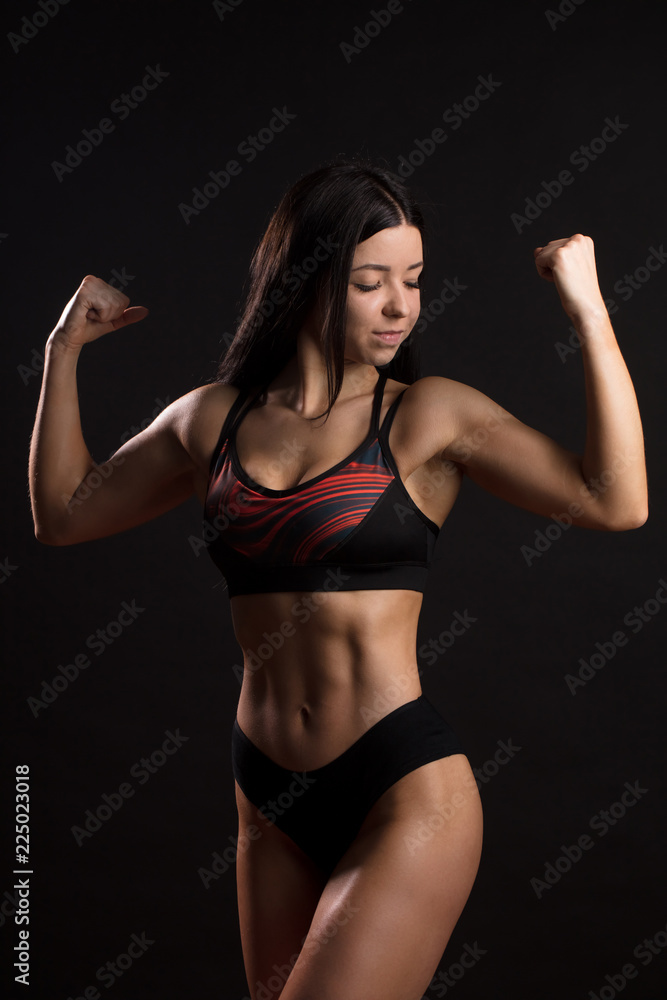 Sporty sexy girl with great abdominal muscles in black sportswear. Tanned  young sexy athletic girl. A great sport female body. The girl athlete  demonstrates chiseled biceps. Miss fitness bikini foto de Stock