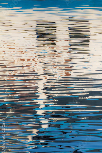 Reflection of windows in the waters of lake created by the light of the setting sun forming different size and shape of glimmer and colors
