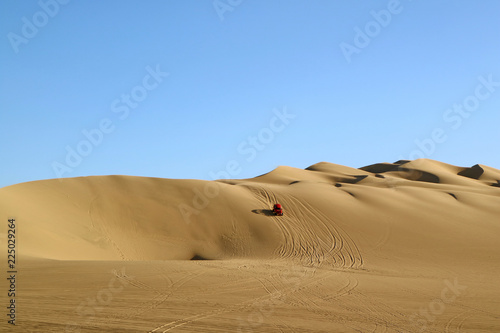 A red dune buggy running on the immense sand dune of Huacachina  Ica region  Peru 