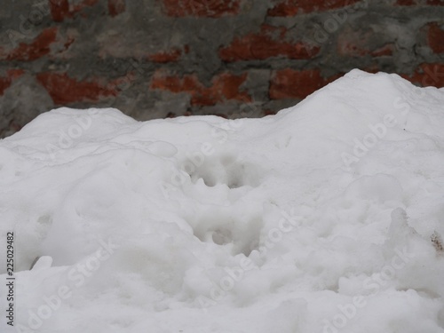 Fluffy white  snow piled up beside a stone wall of a building © raksyBH