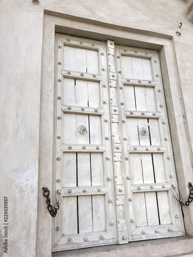 Heavy white wooden door with designs in a building by the roadside. Heavy white wooden door with designs in a building by the roadside.