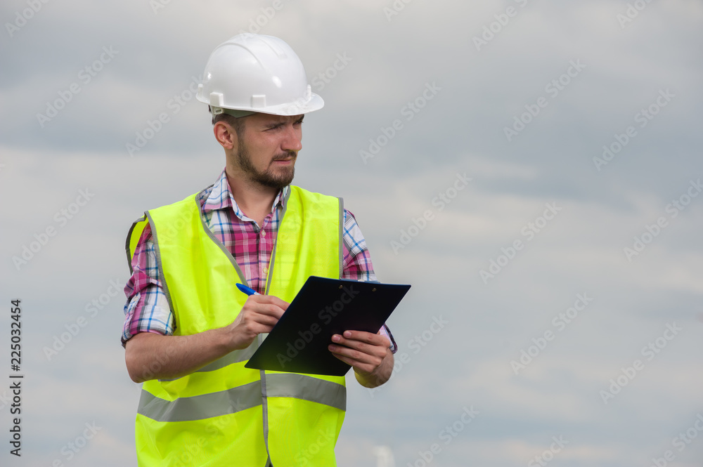Young male engineer in green vest and helmet