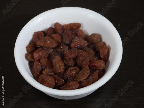 close up of pile of raisins on white background, Kismish, Munnka, Kismish in Whitye Bowl on Wooden Background,Raisins in White Bowl on Wooden Background,