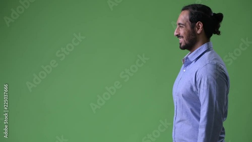 Profile view of young happy bearded Indian businessman smiling