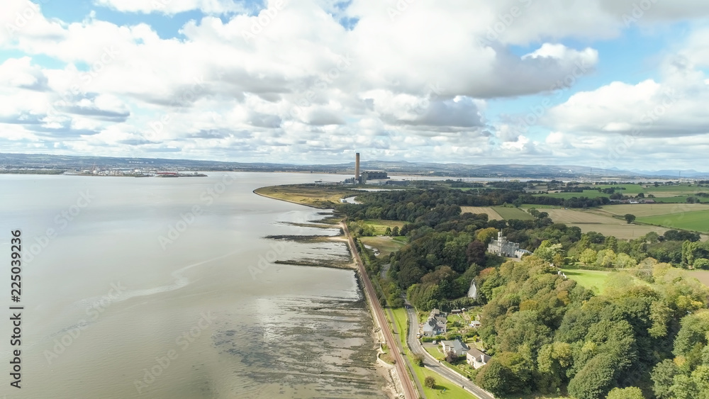 Aerial view to the tall chimney of the disused Longannet Power Station from above the village of Culross.