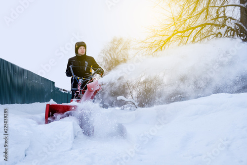 young man removes snow with a snowplower