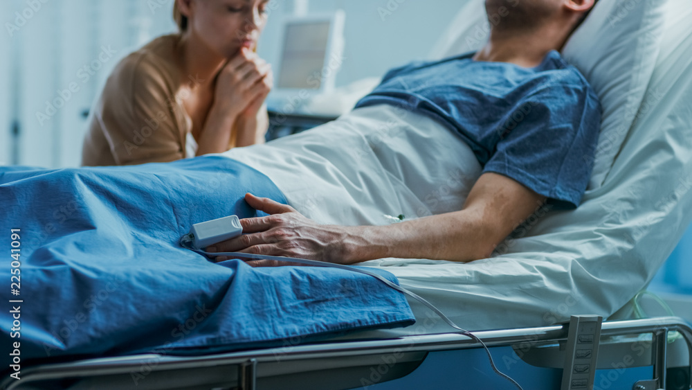 In the Hospital Sick Man Lying on the Bed, His Visiting Wife Hopefully Sits  Beside Him and Prays for His Rapid Recovery. Tragic, Somber and Melancholy  Scene. Stock Photo | Adobe Stock