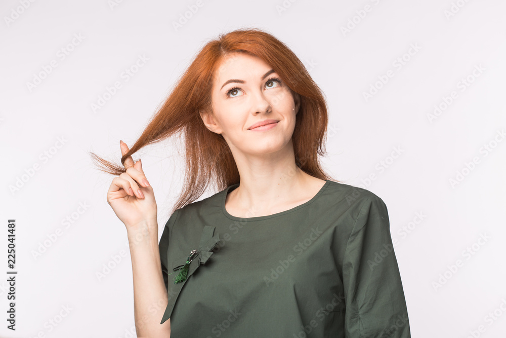 Expressions and people concept - Portrait of a beautiful young woman with red hair thinking over white background Expressions and people concept - Portrait of a beautiful young woman with red hair thinking over white background