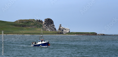 Insel Irland's Eye vor blauem Himmel und Boot im Vordergrund photo