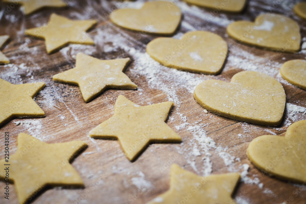 Christmas baking. Making gingerbread biscuits. Cookie dough in heart and star shape on kitchen counter.