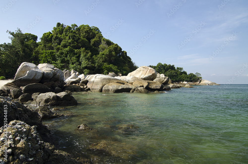 wild tropical island and rocky sea shore under bright sunny day and blue sky background