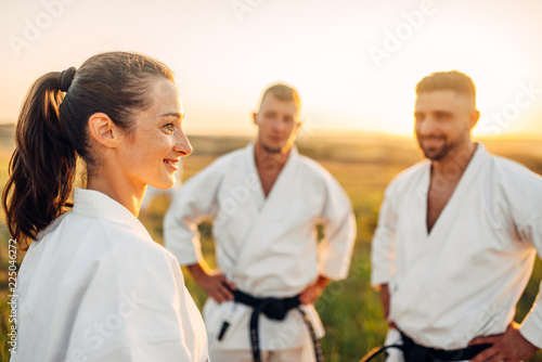 Two male and one female karate fighters in field