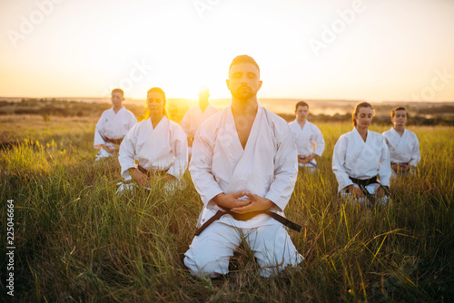 Grupa karate siedzi na ziemi i medytuje