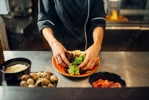 Female chef cooking meat salad on wooden table