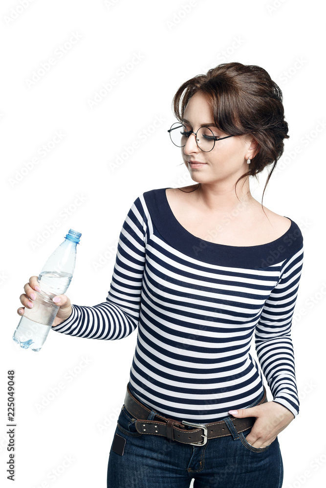 A young woman in a striped tight blouse holds in his right hand a bottle with clean drinking water. A young woman in a striped tight blouse holds in his right hand a bottle with clean drinking water.