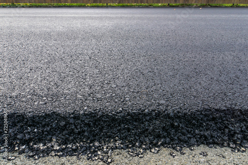 newly laid black bitumen asphalt with a high edge to the gravel