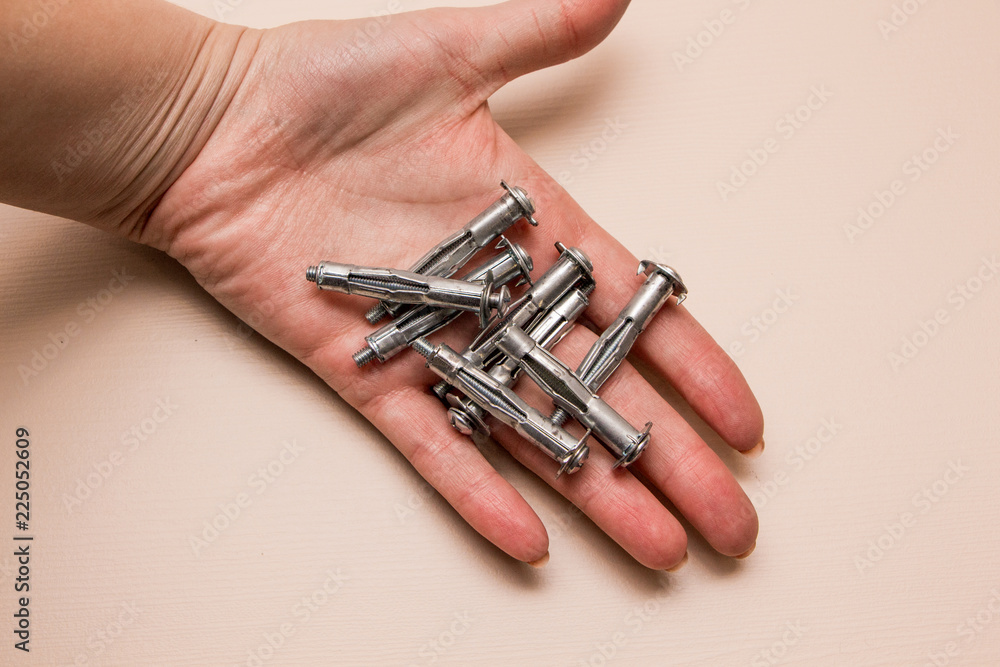 Wall plug or anchor or rawlplug in the hand on a wooden background Wall plug or anchor or rawlplug in the hand on a wooden background