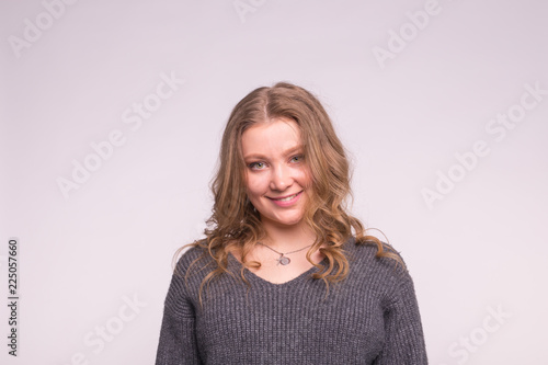 Fashion, style and people concept - portrait of a beautiful young woman with a tender smile she looks at the camera over white background with copy space