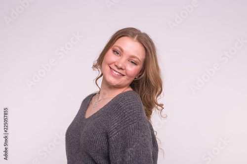 Portrait of fashionable young blonde woman with curly hair in grey cardigan on white background