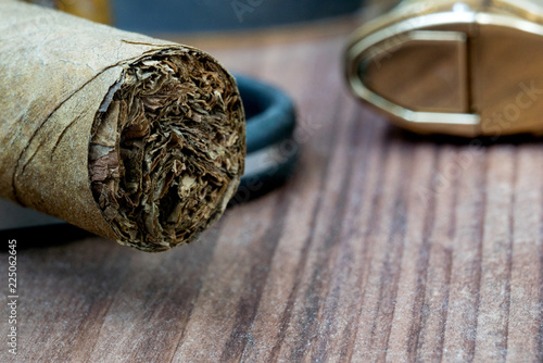 Photo of a close-up of a cigar lying on a guillotine and lighters in the background
