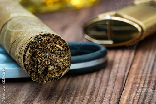 Photo of a close-up of a cigar with a guillotine and lighter on wooden table