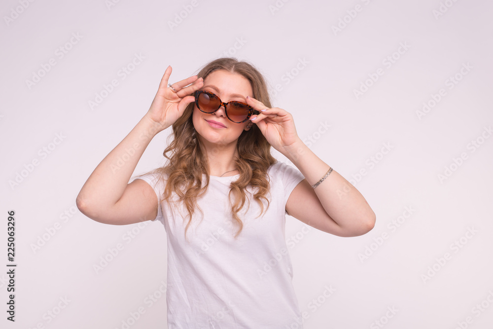 Beautiful white curly young woman wearing white t-shirt and sunglasses on white background Beautiful white curly young woman wearing white t-shirt and sunglasses on white background