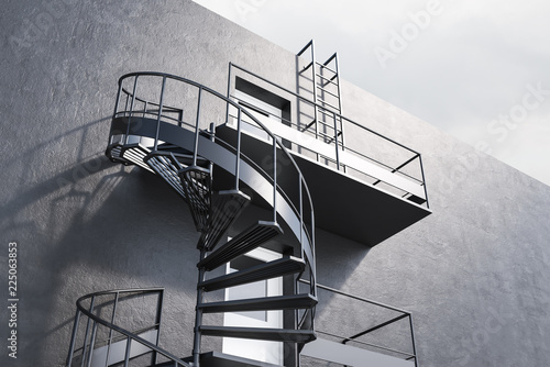 Fototapeta Gray building with spiral fire escape stairs, side