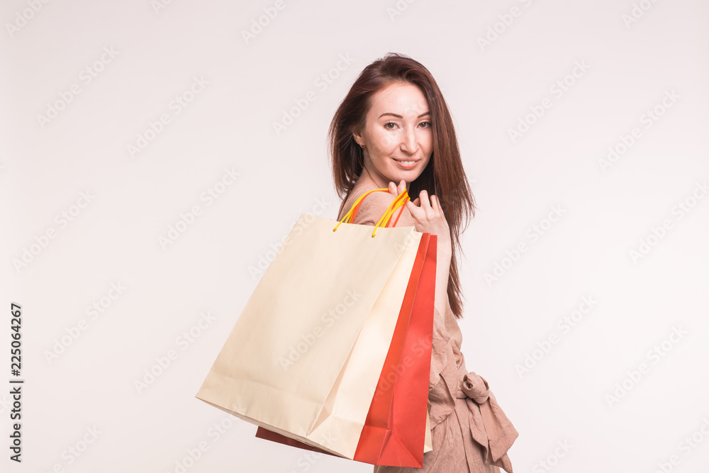 Fashion, shopping and people concept - happy brunette woman with paperbags after shopping on white background
