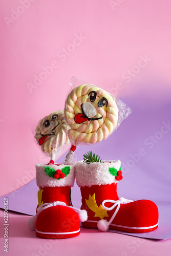 Santa's boot with candy marshmallow on a stick with a smile on the duotone background