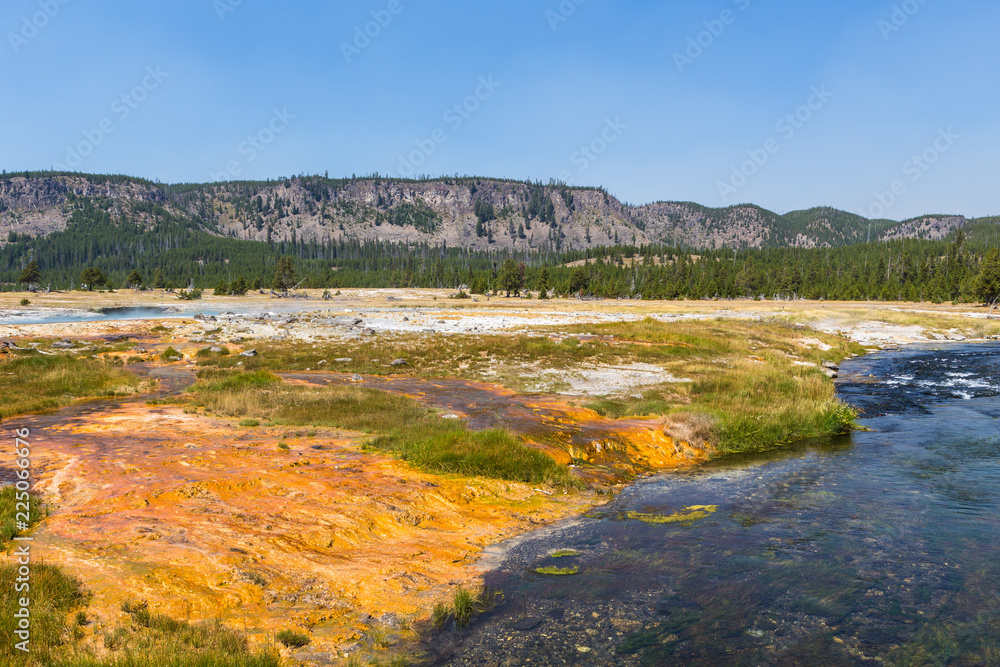River bank near hot springs with multi-colored edges, Yellowstone National Park, USA