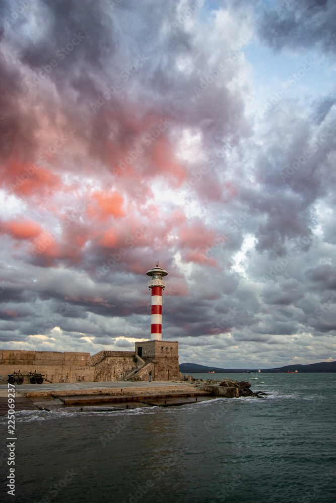 Lighthouse in the port before the storm. Dramatic sky.