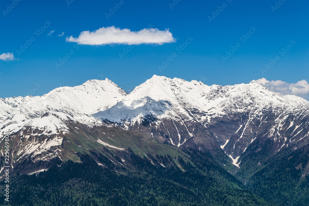 Snowy mountain tops with clouds in the blue sky