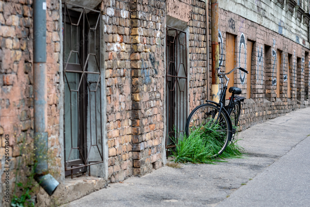 Fototapeta Przy starym ceglanym budynku rynienki z zamkiem łączyły czarny rower.