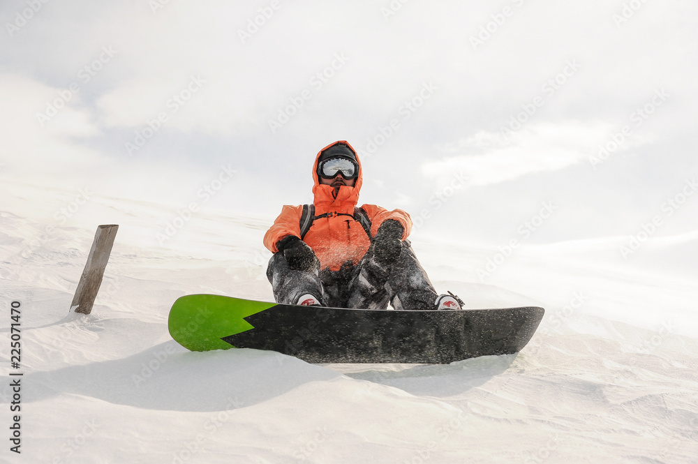 Male snowboarder riding down the mountain hill on the board