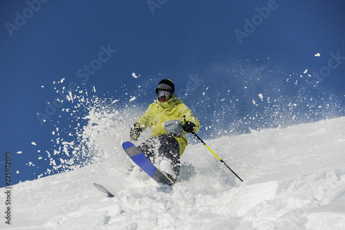 Skier dressed in yellow sportswear riding down the slope in Georgia, Gudauri