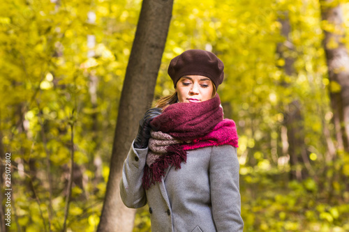 Fall, nature and people concept - Young beautiful woman in grey coat standing in autumn park © satura_