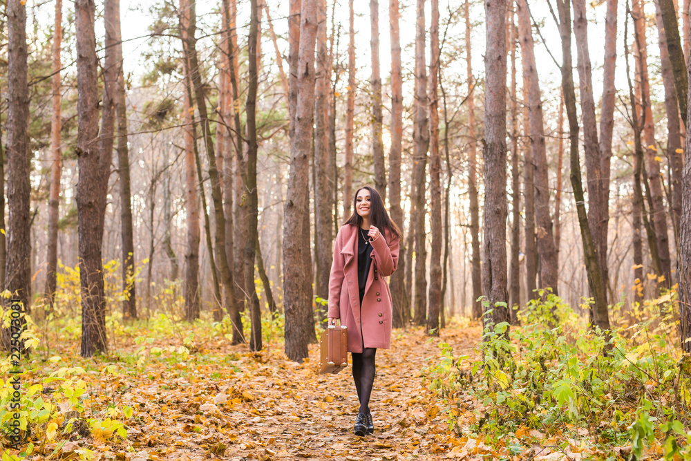 Young stylish woman with retro suitcase walking in autumn park Young stylish woman with retro suitcase walking in autumn park