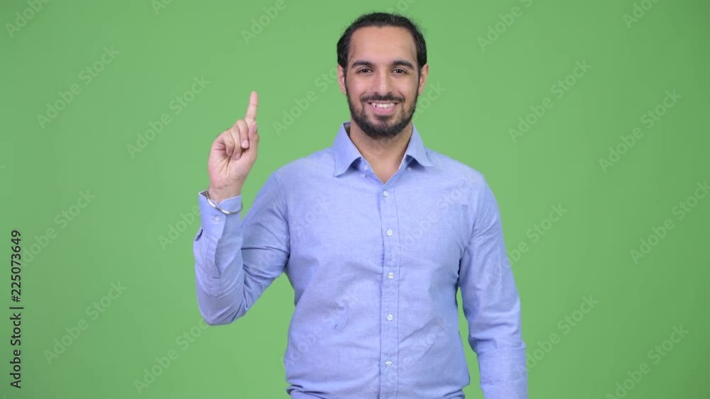 Young happy bearded Indian businessman pointing up Young happy bearded Indian businessman pointing up