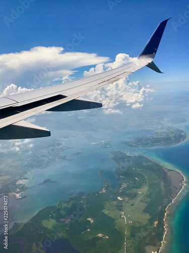 Freedom: Aerial view from above the clouds with a wing of an airplane in the sky over Cuba approaching the city of Havana (scenic journey over the ocean with beautiful view and cloudscape)