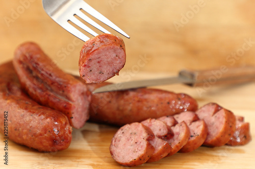 A piece of smoked juicy sausage on a fork