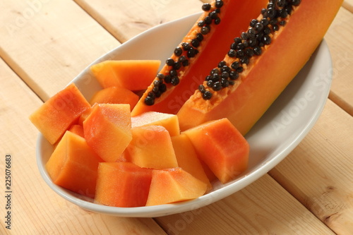 Two slices of papaya fruit with diced papaya in a bowl