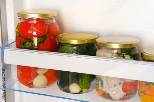 Jars of various homemade pickled vegetables on shelf of refrigerator. Fermented healthy natural vegetarian food concept.
