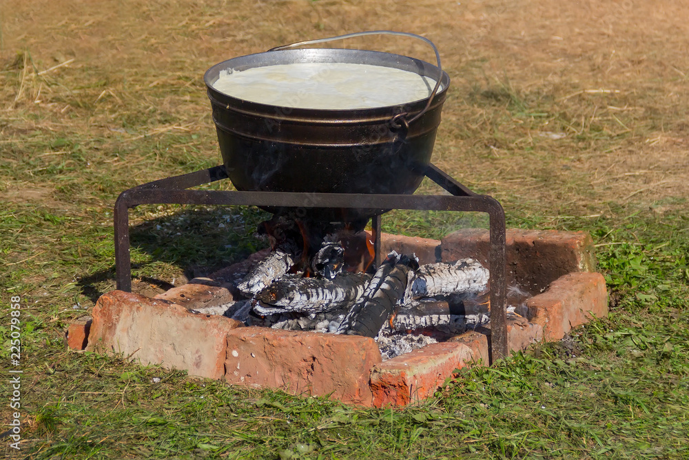 caldron with boiling milk for cooking Adyghe cheese on fire close-up caldron with boiling milk for cooking Adyghe cheese on fire close-up